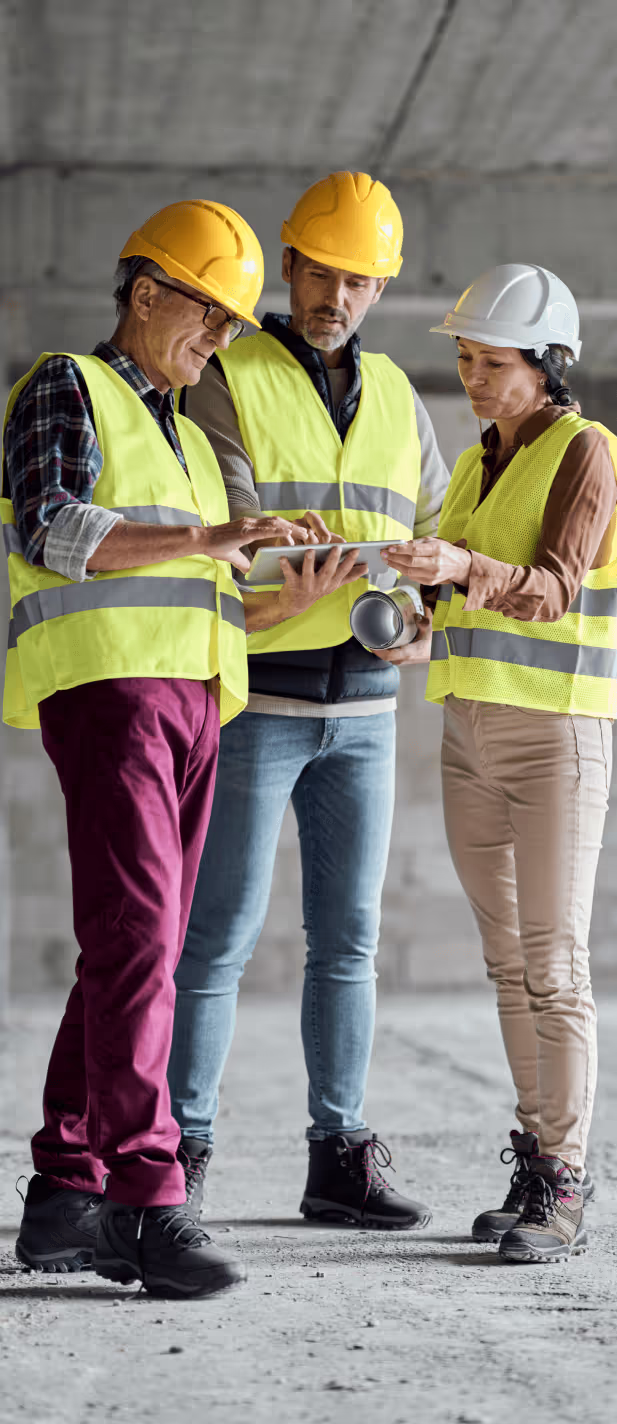 Three Caucasian engineers discussing plans at a construction site